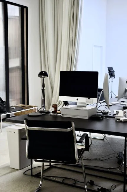 Minimalist office desk with laptop, glasses, and green brainstorming poster for fresh ideas.